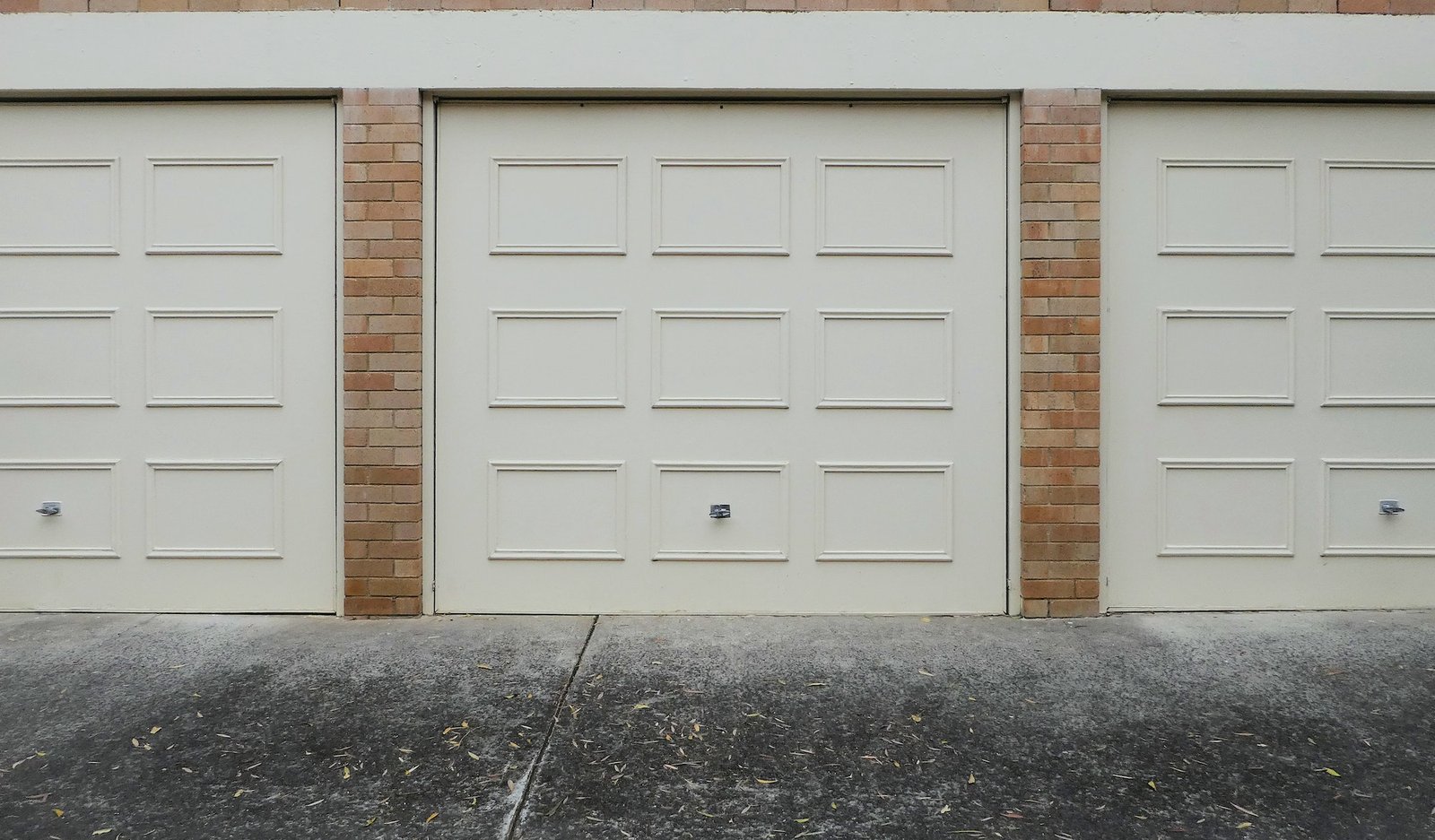 cream garage doors with wood panels on blonde brick wall